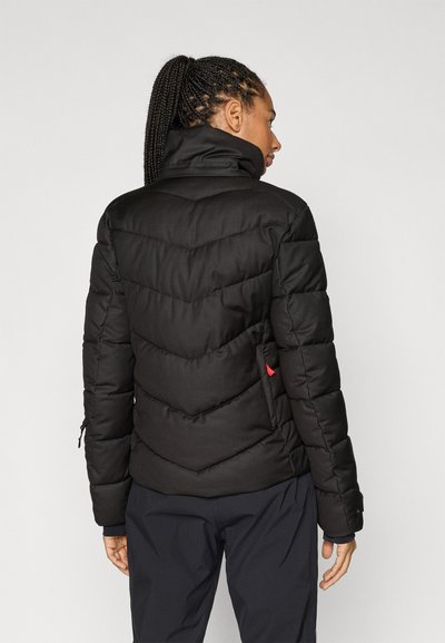 Μαύρο μπουφάν κοντό με ραφές σε σχήμα V (chevron), ψηλό γιακά και πλαϊνή τσέπη με κόκκινη λεπτομέρεια. Ομαλή υφή, σχεδιασμένο για ζεστασιά και άνεση.