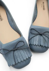 Ballerines en cuir bleu avec un bout arrondi, des franges à l'avant et un nœud décoratif. Doublure intérieure douce.