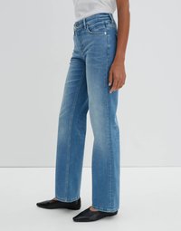 Light blue wide-leg jeans made of denim, featuring a mid-rise waist, slight fading, and silver-tone hardware. Worn with black pointed flats.