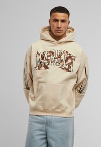 Beige hettegenser med stor "MARKET" tekst, broderte fugledesign, kengurulomme og svarte linjeakenter på ermene.
