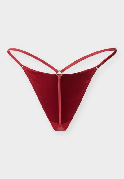 Κόκκινο βελούδινο στρινγκ με λεπτές ρυθμιζόμενες τιράντες και κεντρικό μεταλλικό κρίκο που συνδέει το μπροστινό panel με τη ζώνη μέσης.