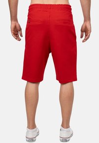 Rode short met een elastische tailleband, voorzien van twee achterzakken. Gemaakt van zacht materiaal, hebben ze een knielengte snit en een gladde textuur.