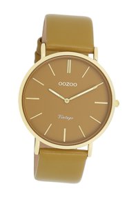 Montre-bracelet marron avec un boîtier doré, des index horaires dorés et des aiguilles dorées. Dotée d'un bracelet en cuir marron et du texte "Vintage" sur le cadran.