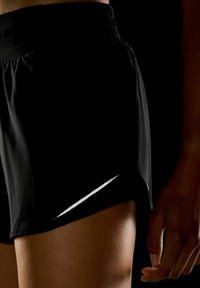 Pantalones cortos deportivos negros con una tela texturizada, que cuentan con un ribete reflectante plateado en el lateral y una cinturilla elástica para mayor comodidad.