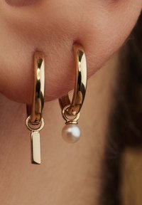 Goldene Creolen mit glatter Oberfläche, einem rechteckigen Anhänger und einer kleinen, befestigten weißen Perle. Entworfen für Ohrlöcher.