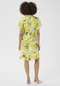 Īsām piedurknēm tērps spilgti dzeltenā, zaļā un zilā pikselētā rakstā, ar brīvu piegriezumu un krāšņām piedurknēm.