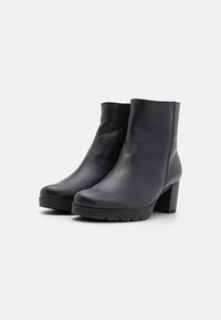 Boots negre din piele până la gleznă, cu o textură netedă, dotate cu un călcâi masiv și o talpă din material cauciucat pentru o aderență și stabilitate sporite.