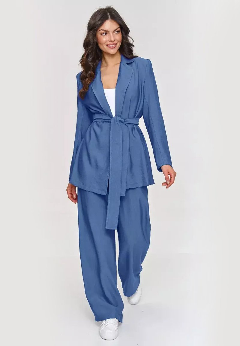 Niebieska marynarka z paskiem w talii o dopasowanym kroju, zestawiona z szerokimi spodniami. Wykonana z teksturowanej tkaniny, z kołnierzem klapowym i luźną sylwetką.