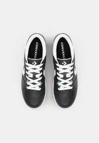 Black leather sneakers with white rubber sole and laces. Features a white star logo and contrasting white side panels.