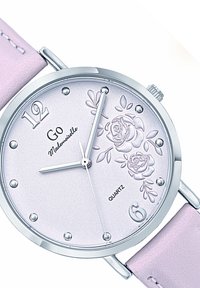 Montre à quartz avec un boîtier argenté, un bracelet texturé rose et un cadran rose clair affichant des roses en relief, des index heures argentés et des aiguilles.