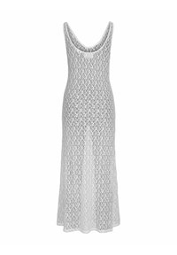 Largo vestido blanco hecho de un material parecido al encaje, con escote en forma de barco y un dobladillo acampanado con un diseño suelto y aireado.