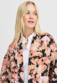 Kimono s cvjetnim uzorkom u crnoj, ružičastoj i breskvastoj boji. Lagani materijal, otvoreni prednji dio, duži rukavi i dva prednja džepa.