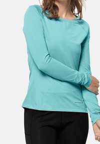 Turkoosi pitkähihainen urheilupaita, joka on valmistettu kevyestä materiaalista, jossa on pyöreä pääntie ja napakka malli, yhdistetty mustiin leggings-housuihin.