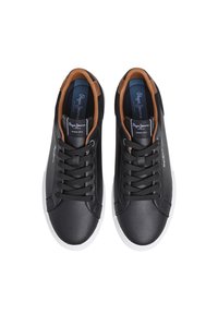 Sorte skinnsneakers med brune detaljer, rund tå og hvite gummisåler. Har svarte lisser og en logo på tungen.