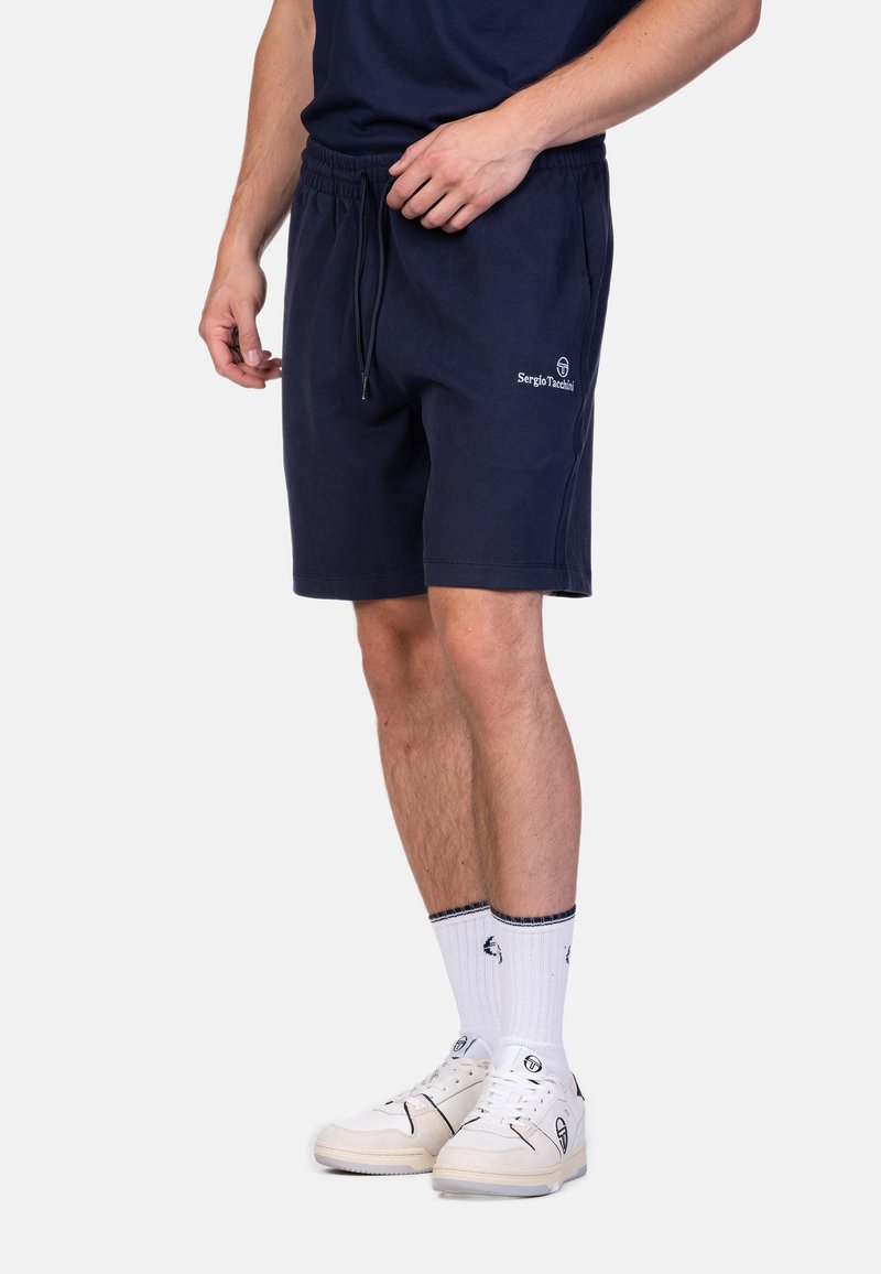 Shorts en coton bleu marine avec taille élastique et cordon de serrage. Présente un logo brodé sur le côté. Coupe décontractée, longueur mi-cuisse.