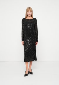 Vestido de noite preto com lantejoulas, mangas longas, decote arredondado e comprimento até ao joelho. Possui uma silhueta ajustada e um padrão floral subtil.