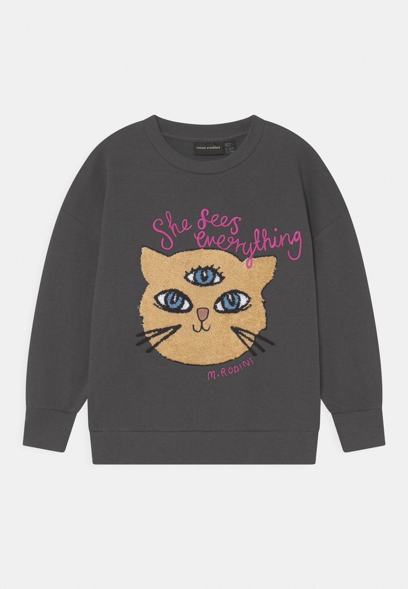 Sweatshirt gris avec un visage de chat brodé, comprenant trois yeux, des iris bleus et des moustaches. Le texte indique "Elle voit tout" en rose.