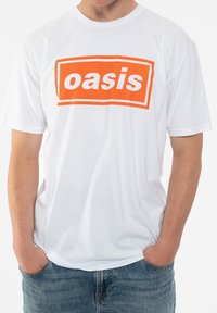 White cotton t-shirt featuring a bold orange rectangular logo that reads "oasis," with a relaxed fit and short sleeves.