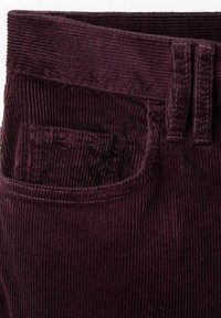 Pantalon en velours côtelé violet foncé en gros plan montrant la ceinture, les passants de ceinture et une poche avant avec une texture côtelée visible.