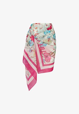 Jupe paréo transparente avec des bordures roses, nouée à la taille, ornée d’un imprimé floral coloré en rouge, bleu et jaune sur fond blanc.