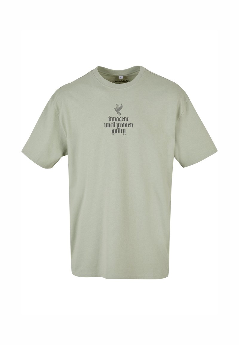 Lys grøn bomulds t-shirt med korte ærmer. Har et gråt trykt design med teksten "uskyldig indtil det modsatte er bevist" og en fuglegrafik.