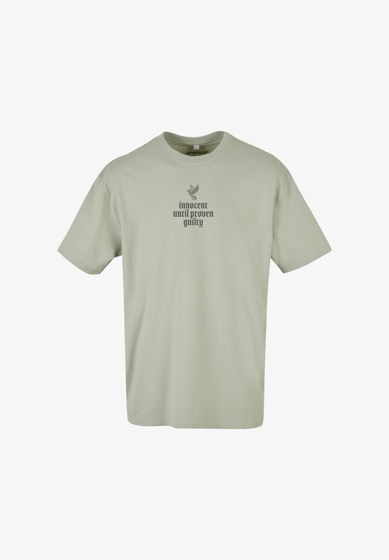 Light green cotton t-shirt with short sleeves. Features a gray printed design with the text "innocent until proven guilty" and a bird graphic.