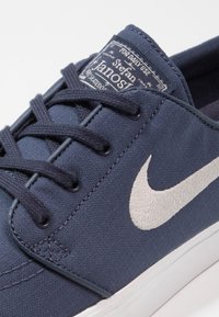 Scarpa da skate Nike Stefan Janoski blu navy con il logo Nike bianco, parte superiore in tessuto e lacci blu navy abbinati su suola bianca.