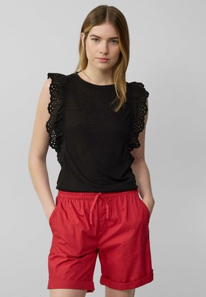 Haut sans manches noir avec des accents en dentelle découpée à volants sur les épaules, associé à un short rouge avec une taille élastique et des poches.