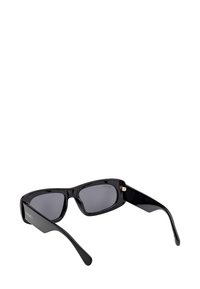 Černé obdélníkové sluneční brýle s tlustými lesklými rámy a tmavě zabarvenými skly, nakloněné tak, aby bylo vidět vnitřní strany nožiček.