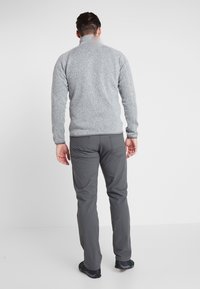 Gray fleece pullover with a high collar, paired with dark gray pants. The fabric has a textured appearance, providing a casual fit.