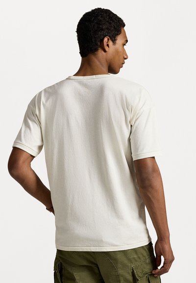 Crème-kleurig t-shirt met korte mouwen en een relaxte pasvorm, met een ronde halslijn en een zachte, textuurstof. Achteraan is er minimale detaillering zichtbaar.
