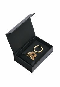Gold keychain with a raised "B" design, presented in a black gift box with a satin ribbon and a black interior.