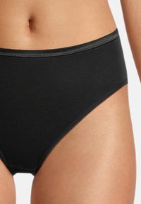 Slip in cotone nero con una texture liscia, dotati di una vita larga e bordi puliti. Il design offre una copertura totale e una vestibilità classica.