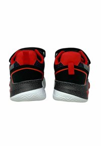 Scarpe sportive nere e rosse con un accento grigio testurizzato, caratterizzate da un collo imbottito, una cinghia regolabile e una suola bianca con motivo a zigzag.