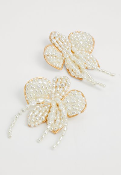 Pince à cheveux en perles blanches en forme de papillon avec des accents en métal doré. Comprend des perles lisses, ovales et en forme de goutte d'eau, rehaussant la texture et le design.
