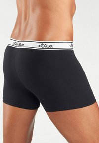 Black boxer shorts with a white waistband featuring the "s.Oliver" logo, made from smooth material, close-fitting design, mid-thigh length.