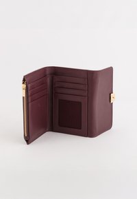 Burgundy leather wallet with a zip compartment, multiple card slots, and a clear ID pocket. Gold-tone hardware detail. Smooth texture.