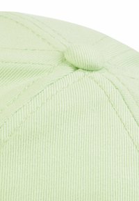 Lichtgroene pet met een corduroy-textuur, voorzien van een knop bovenop en zichtbare stiksels in een ruitpatroon rondom de kroon.