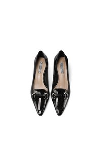 Décolleté in pelle verniciata nera con punta affusolata, dotate di una fibbia decorativa argento nella parte anteriore e una soletta beige liscia.