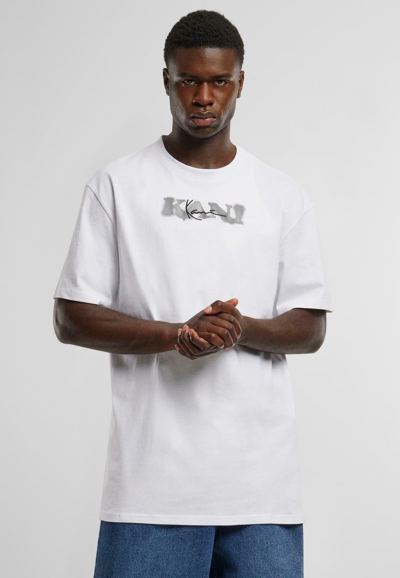 White cotton t-shirt with a round neckline and short sleeves, featuring a stylized gray graphic text "KAN" at the center.