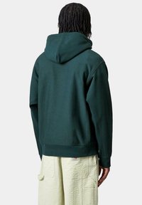 Sudadera con capucha de color verde oscuro, con un corte relajado, que presenta un bolsillo tipo canguro y puños de canalé. Tejido texturizado, suave y con costuras mínimas.