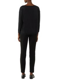 Zwarte gebreide sweater met een wijde halslijn, lange mouwen en een relaxte pasvorm, gecombineerd met slanke zwarte broek en zwarte schoenen.