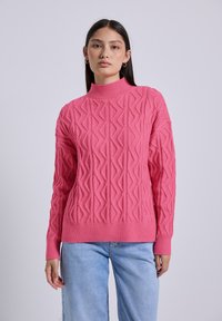 Pletený pulovr v živé růžové barvě s vysokým límcem a texturovaným geometrickým vzorem. Úzké manžety a lem, s volným střihem.