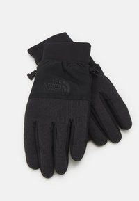 Gants noirs en matériau doux et extensible, présentant une surface de préhension texturée, des poignets élastiques et un logo au niveau du poignet.