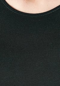 Zwarte geribbelde tanktop met een ronde halslijn en een gestructureerde afwerking. De stof lijkt rekbaar en aansluitend, wat de eenvoud van het ontwerp benadrukt.