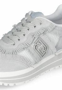 Sneaker grigio con dettagli in suede, mesh e frange, con occhielli in metallo e un accento con logo sul lato. Suola spessa bianca.