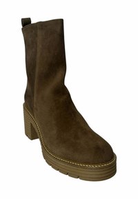 Botín de ante marrón hasta el tobillo con un tacón de bloque grueso, parte superior texturizada, tirador y costuras en contraste a lo largo de la suela.