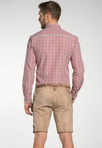 Rood en wit geblokt shirt met lange mouwen; lichtbruine shorts met een gestructureerde afwerking en zijknopen; van achter bekeken.