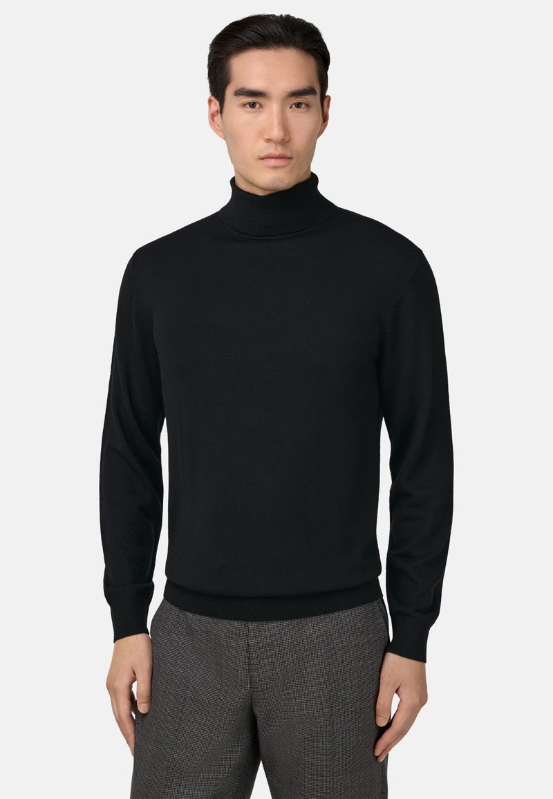 Černý rolák vyrobený z hladké pleteniny, s dlouhými rukávy a přiléhavým, žebrovaným lemem a límcem. Nosený s kostičkovanými kalhotami.