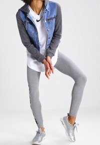 Denim and gray hoodie jacket with front pockets, white Nike shirt, gray leggings with side logo, and silver athletic shoes.